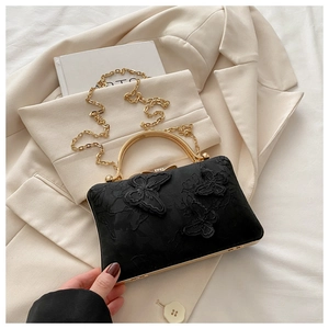 Close-up of butterfly floral embroidery and gold metal ring handle on black bag