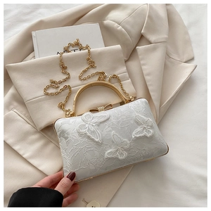 Detail of butterfly embroidery and rhinestone clasp on a creamy white evening clutch bag