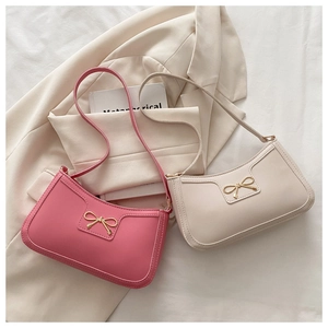 Détail de sacs à bandoulière rose et crème avec boucles de nœud dorées élégantes