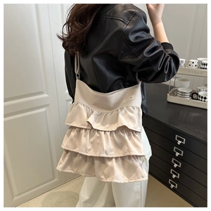 Detail of light beige ruffled shoulder bag showing three layers of soft fabric ruffles