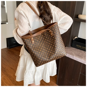 Detail of a large vintage brown monogram tote bag styled with a white pleated dress