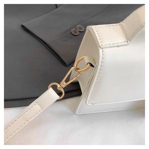 Detailed macro shot of pale gold metal hardware and fine stitching on a white leather handbag