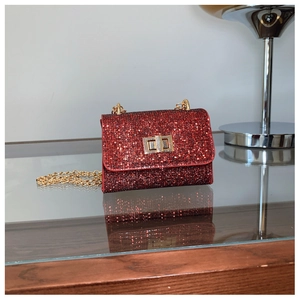 Détail du sac à main rouge à paillettes avec bandoulière chaîne dorée et fermoir métallique