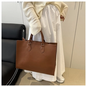 Detail of large brown tote bag with crocodile texture and sturdy top handles for women