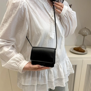 Minimalist black PU leather small crossbody bag for women in a lifestyle home setting