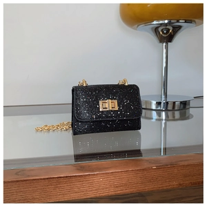 Détail du mini sac noir à paillettes avec fermoir carré doré et bandoulière chaîne