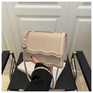 Macro shot of ivory pebbled leather shoulder bag with scalloped edges and chain strap