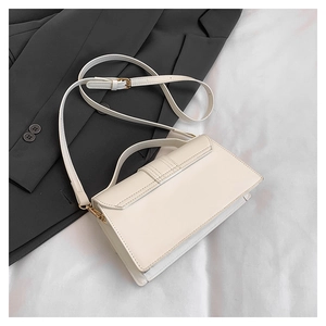 Flat lay of a beige leather flap crossbody bag on a black blazer with golden buckles