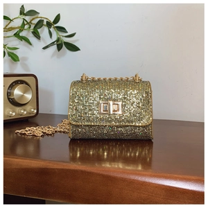 Détail du sac bandoulière à paillettes avec chaîne dorée et fermoir sur table