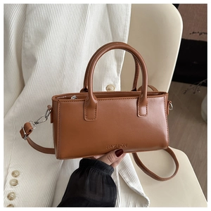 Detail view of brown leather bag with embossed fashion logo and adjustable strap