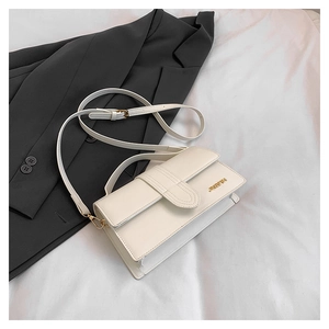 Detail of white leather crossbody bag with gold metal logo and sleek top handle