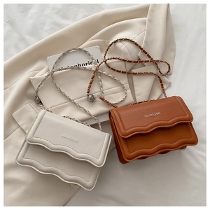 Detail of lychee pattern leather bags with wave flap and woven metal chain straps