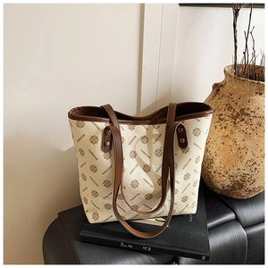 Detail shot of vintage beige printed tote bag on leather bench with decorative props