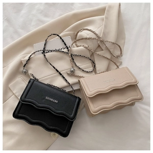 Detail of crossbody bag with wavy edge flap, litchi texture, and silver ball chain strap