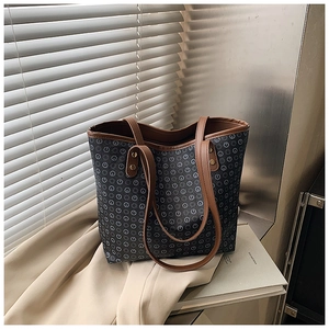 Detail of vintage tote bag with grey monogram pattern and brown leather handle