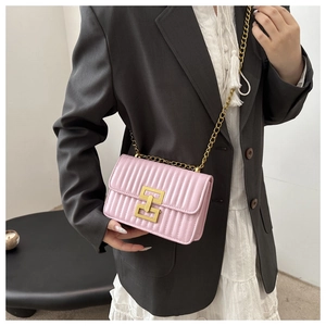 Détail du sac bandoulière rose clair matelassé avec chaîne dorée et fermoir carré en métal