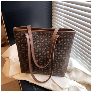 Detail view of large vintage tote bag with retro monogram pattern and leather handles