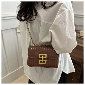 Détail du sac en cuir gaufré marron avec fermoir géométrique doré et bandoulière chaîne