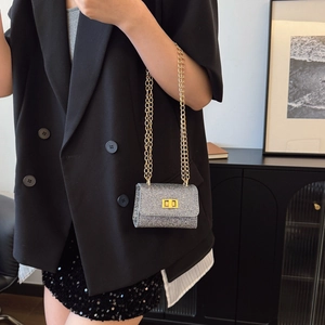 Mini sac bandoulière argenté pailleté avec chaîne dorée porté par un mannequin