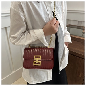 Détail du sac en cuir matelassé bordeaux avec chaîne dorée et fermoir géométrique en métal