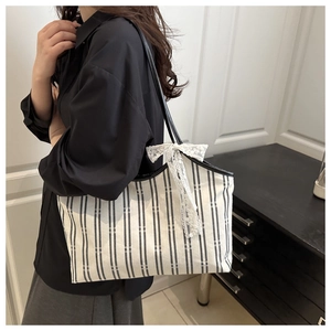 Detailed shot of large striped canvas tote with lace bow on a model's shoulder