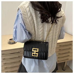 Détail du petit sac à bandoulière noir matelassé avec chaîne dorée sur mannequin