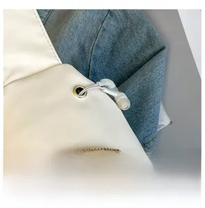 Detail of white leather chest bag featuring a built-in gold headphone port with cable