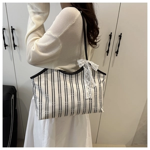 Detail showing white lace bow on black and white striped canvas tote bag with shoulder strap
