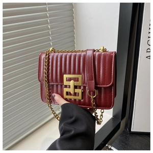 Détail du sac matelassé bordeaux avec boucle dorée élégante et bandoulière en chaîne