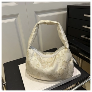 Détail de la broderie papillon en satin blanc sur ce sac à main hobo chic pour femme
