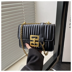 Détail du sac matelassé noir avec fermoir géométrique doré mat et bandoulière chaîne