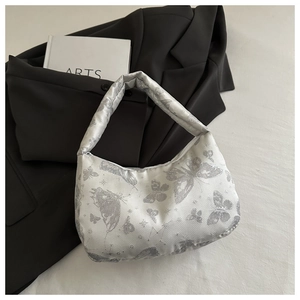 Détail macro du tissu jacquard papillon et de la poignée rembourrée de ce sac hobo blanc
