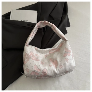 Gros plan du tissu jacquard blanc perle avec motifs papillons roses sur le sac à main