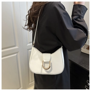 Detail of white leather hobo bag featuring a gold horseshoe metal buckle and shoulder strap