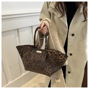 Close-up of leopard print tote bag with gold logo plate and autumn styling detail