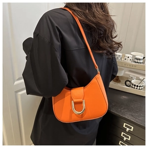 Close-up of bright orange hobo bag with a silver horseshoe metal buckle and smooth leather finish