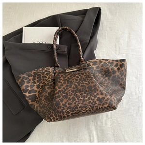 Chic leopard print tote bag styled with a black blazer and book on white texture