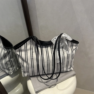 Striped canvas tote bag with lace bow decoration and faux leather trim shown on white pedestal