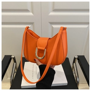 Close-up of vibrant orange crescent handbag with elegant gold U-shaped metal buckle
