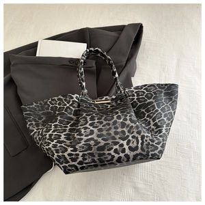 Detail of leopard print tote bag with golden metal trim on a stylish suit background