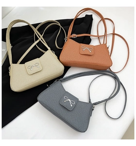 Detailed view of three baguette bags with metal bows in beige, tan, and dark grey colors