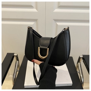 Detail of minimalist black crescent bag with vintage gold D-buckle hardware and strap
