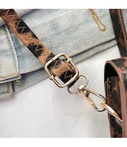 Detail of leopard print leather shoulder strap with gold buckle and lobster clasp