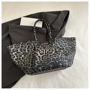 Detailed view of the leopard print tote bag with metallic logo on a grey blazer