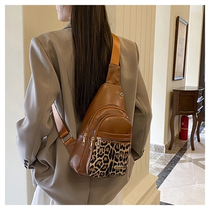 Brown leather chest bag with leopard print accent shown on model in a soft warm setting