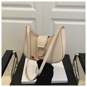 Detail of a creamy leather saddle bag featuring a large gold D-shaped buckle and strap
