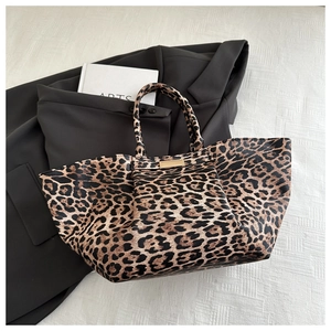 Detailed top view of a leopard print tote bag with gold metal plate on white background