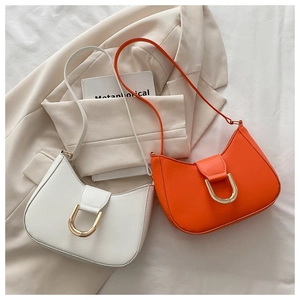 Detail of white and orange crescent shoulder bags with gold hardware on a suit jacket