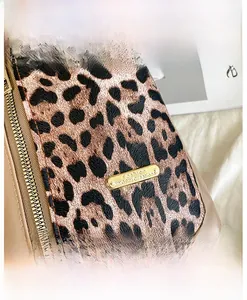 Close-up of leopard print chest bag with gold metal logo and brown faux leather trim