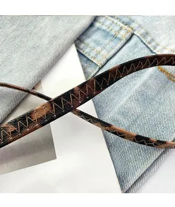 Detail of leopard print faux leather strap with orange V-shaped stitching on denim